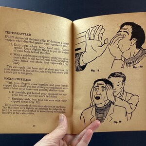 May include: Open book with illustrations and text on self-defense techniques. The illustrations depict hand gestures and facial expressions. The text includes instructions for various moves, such as the "Teeth-Rattler" and "Boxing the Ears."