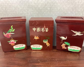 May include: Three red wooden boxes with lids, each decorated with painted images of birds and flowers. The center box has Chinese characters. Each box has a green and white label with text.