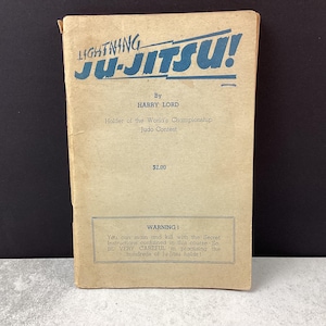 May include: Vintage "Lightning Ju-Jitsu!" book with blue text on a tan cover. The book, by Harry Lord, details Judo techniques. A warning about the secret instructions is printed at the bottom. The book is a collectible item.
