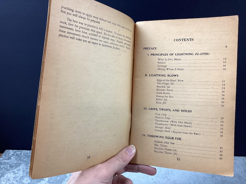 May include: Open book with aged, tan pages. The right page displays the "CONTENTS" with sections like "PRINCIPLES OF LIGHTNING JU-JITSU" and "LIGHTNING BLOWS." The left page has text about practicing and applying defense.