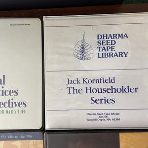 May include: Three cassette tapes with white labels and black text. The first tape is titled "Spiritual Practices & Perspectives for Daily Life" and features a drawing of a person with their eyes closed. The second tape is titled "Dharma Seed Tape Library Jack Kornfield The Householder Series" and features a drawing of a leaf. The third tape is titled "12 Sessions - Sanity Path".