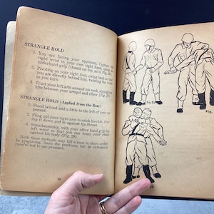 May include: Open book with illustrations and text on self-defense techniques. The pages are aged with text and diagrams showing various strangle holds. The book is open, revealing the illustrations.
