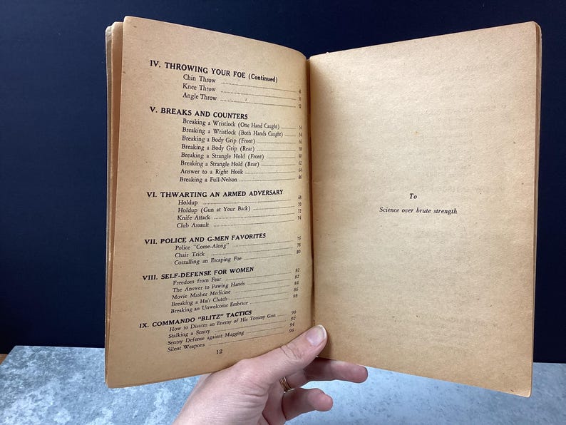 May include: Open vintage book pages with a table of contents on self-defense techniques. Sections include throwing, breaks, counters, thwarting armed adversaries, police tactics, and self-defense for women. The text "Science over brute strength" is visible.