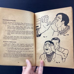 May include: Open book with illustrations and text on self-defense techniques. The illustrations show figures demonstrating hand strikes and ear boxing. The text includes instructions on how to perform the techniques.