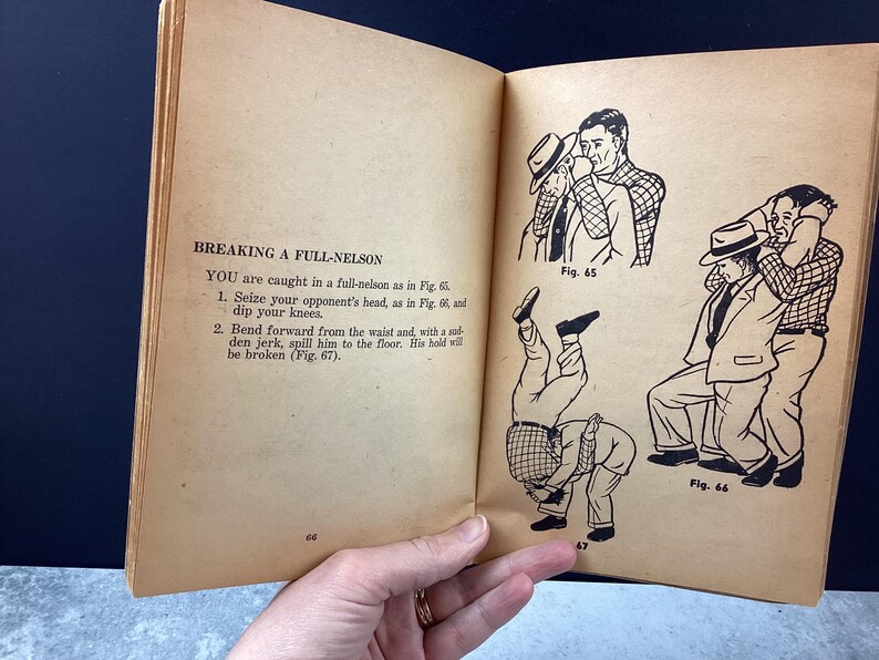 May include: Open book page with text "BREAKING A FULL-NELSON" and instructions on how to break a full-nelson wrestling hold. Includes black and white illustrations of the wrestling move. The page is aged with a yellowed tone.
