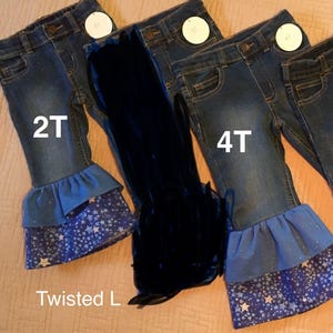 May include: Three pairs of blue denim jeans with a ruffled hem and a star print. The jeans are labeled 2T, 4T, and 4T. The brand name "Twisted L" is visible on the bottom left.