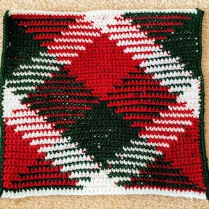 May include: A crocheted square with a geometric pattern in red, white, and green.