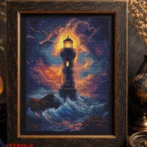 May include: A framed cross-stitch artwork depicting a lighthouse standing on rocky terrain amidst a stormy sea. The scene features a glowing yellow lantern room, dark blue and orange clouds, and crashing waves. The word FEERIQUE is printed in red.