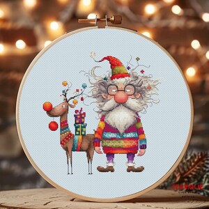 May include: Cross stitch pattern featuring a colorful Santa Claus with a white beard and glasses, holding a gift, and a reindeer with red pom-poms.