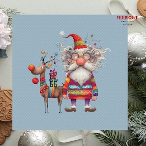 May include: A cross stitch pattern featuring a whimsical Santa Claus with a long white beard and a reindeer with a red nose. Santa is wearing a colorful sweater and a red hat. The reindeer is carrying a stack of presents. The pattern is on a light blue background.