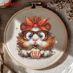 May include: Cross-stitch pattern of a surprised hamster wearing glasses and a red headband, holding a popcorn container. The hamster has large blue eyes and is surrounded by popcorn kernels. The design is set in a wooden embroidery hoop.