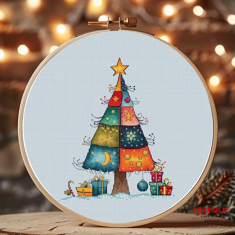 May include: A cross stitch pattern of a colorful patchwork Christmas tree with a star on top and presents at the base. The tree is on a light blue background.