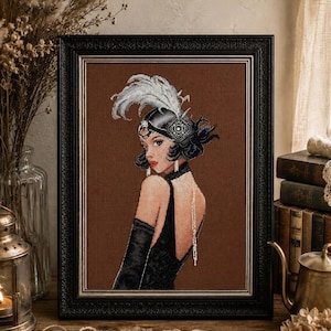 May include: A framed cross-stitch embroidery depicting a person with dark hair wearing a black headpiece with a white feather, a black dress, and long black gloves. The figure is shown from the back, looking over their shoulder against a brown background.