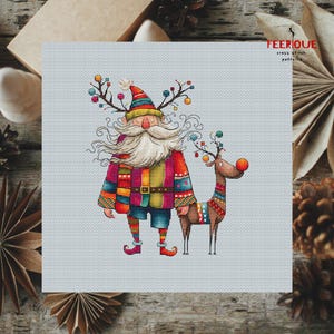 K&ouml;nnte beinhalten: Ein farbenfrohes Kreuzstichmuster mit einem skurrilen Weihnachtsmann mit langem wei&szlig;em Bart und einem Rentier mit roter Nase. Der Weihnachtsmann tr&auml;gt einen rot-gr&uuml;n-gelb-blau gestreiften Pullover und eine blaue Hose. Das Rentier tr&auml;gt einen bunten gestreiften Pullover. Das Muster ist auf einem hellblauen Hintergrund.