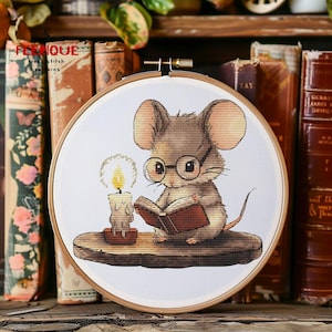 May include: A brown mouse wearing glasses sits on a wooden ledge and reads a book. A lit candle sits next to the mouse. The image is in a round embroidery hoop.