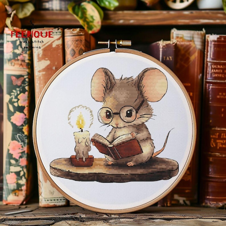 May include: A brown mouse wearing glasses sits on a wooden ledge and reads a book. A lit candle sits next to the mouse. The image is in a round embroidery hoop.