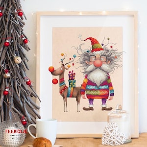 May include: A cross stitch pattern featuring a whimsical Santa Claus with a long white beard and glasses, wearing a colorful sweater and a red hat. He is standing next to a reindeer with a red nose and colorful decorations. The pattern is framed and displayed on a table with a Christmas tree in the background.