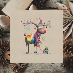 May include: A colorful cross-stitch pattern of a reindeer wearing a rainbow-colored scarf and hat, holding a gift box. The reindeer is surrounded by snowflakes and red ornaments.