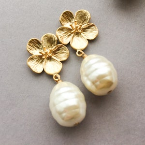 May include: Gold flower earrings with a large white pearl dangling from each flower.