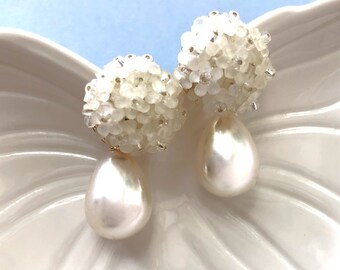 May include: A pair of white pearl drop earrings with a cluster of white beads at the top.