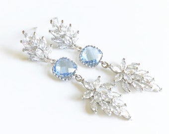 May include: A pair of silver dangle earrings with light blue teardrop-shaped stones and crystal accents.