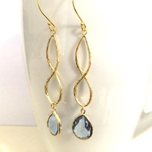 May include: Gold infinity dangle earrings with light blue teardrop-shaped crystals.