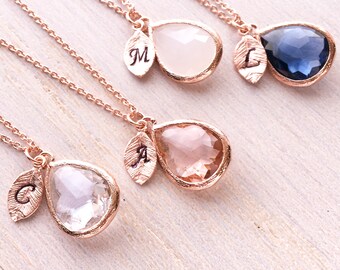 May include: Four rose gold necklaces with teardrop-shaped crystal pendants. Each pendant has a small leaf charm with an initial engraved on it. The initials are C, A, L, and M.