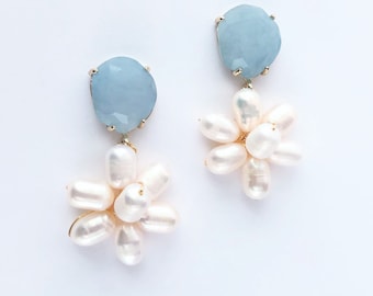 May include: A pair of dangle earrings with a light blue gemstone and a cluster of white pearls in the shape of a flower.