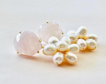 May include: A pair of gold-toned earrings featuring a large, faceted, light pink gemstone and a cluster of white pearls. The earrings have a floral design, with the pearls arranged to resemble flower petals.