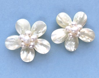 May include: A pair of white flower-shaped earrings with pearl accents.