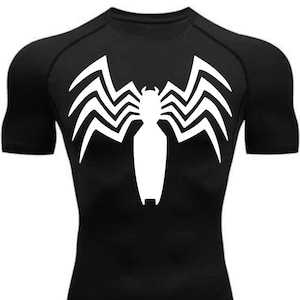 Puede incluir: Camiseta negra de manga corta con un símbolo de Venom blanco en la parte delantera.
