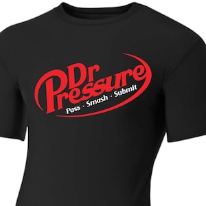 May include: Black t-shirt with a red oval logo that says "Dr Pressure" with the tagline "Pass Smash Submit" underneath.