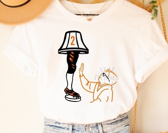 Pode incluir: Camiseta branca com um gráfico de um personagem do filme "Uma História de Natal" segurando uma lâmpada com o número "2" nela.