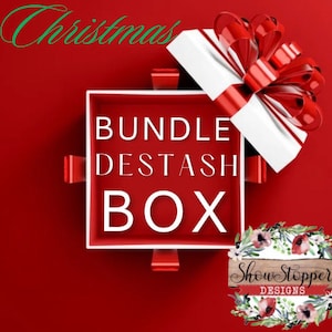 May include: A red gift box with a white interior and a red bow. The box is open, revealing the words "BUNDLE DESTASH BOX" in white. The word "Christmas" is written in green script at the top. A floral design with the text "Show Stopper DESIGNS" is at the bottom.