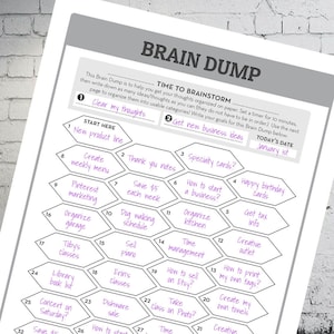 Puede incluir: Una hoja de trabajo de descarga cerebral imprimible en blanco y negro con una cuadr&iacute;cula hexagonal. La hoja de trabajo se titula "Brain Dump" e incluye el texto "Time to Brainstorm". La hoja de trabajo est&aacute; dividida en secciones para "Clear my thoughts" y "Get new business ideas". Cada hex&aacute;gono contiene una idea de negocio o una sugerencia de pensamiento, como "Nueva l&iacute;nea de productos", "Crear un men&uacute; semanal", "Notas de agradecimiento", "Tarjetas especiales", "C&oacute;mo iniciar un negocio", "Tarjetas de cumplea&ntilde;os", "Ahorrar 5 &euro; cada semana", "Pasear al perro", "Organizar la cocina", "Obtener informaci&oacute;n fiscal", "Organizar el garaje", "Vender un piano", "Gesti&oacute;n del tiempo", "C&oacute;mo vender en Etsy", "Tomar una clase de fotograf&iacute;a", "Punto de venta creativo", "C&oacute;mo imprimir mis propias etiquetas", "Crear mis propias toallas", "Clases de Toby", "Lista de libros de la biblioteca", "Clases de Erin", "Venta de vajilla", "Concierto el s&aacute;bado", "Ahorrar 5 &euro;", "C&oacute;mo empezar", "Tiempo", "Creativo".