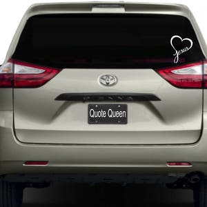 May include: A silver minivan with a black rear window. The window has a white vinyl decal with a heart and the word "Jesus" inside the heart.