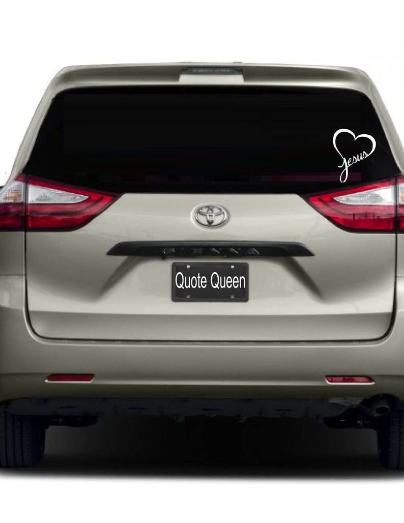 May include: A silver minivan with a black rear window. The window has a white vinyl decal with a heart and the word "Jesus" inside the heart.