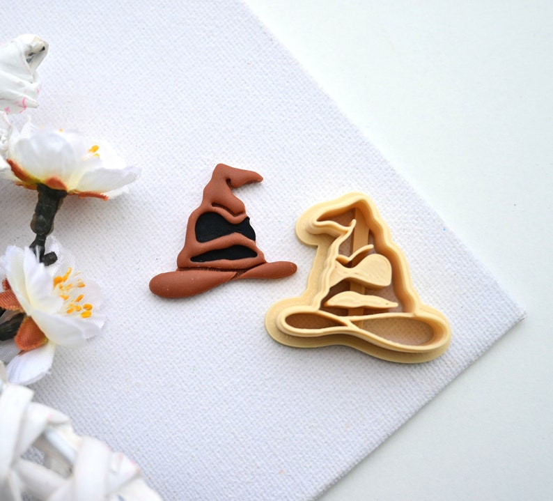 Op de afbeelding: Een bruine en zwarte fondantkoekjesvorm in de vorm van een tovenaarshoed. De vorm is gemaakt van plastic en is ontworpen om koekjes uit te steken in de vorm van een tovenaarshoed.