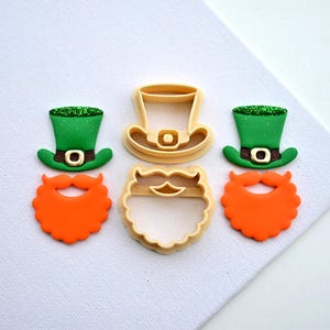Op de afbeelding: Drie koekjesvormen om een ​​kabouter te maken. De vormen zijn voor de hoed, de baard en het gezicht. De hoed is groen met een gouden gesp, de baard is oranje en het gezicht is een eenvoudige ovale vorm.