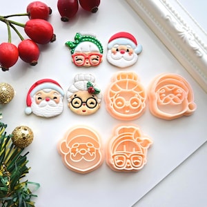 Könnte beinhalten: Eine Sammlung von weihnachtlichen Ausstechformen und dekorativen Akzenten. Das Bild zeigt Designs von Weihnachtsmann und Frau Claus, zusammen mit festlichen Verzierungen wie Beeren und Ornamenten. Die Ausstecher sind in Form von Gesichtern von Weihnachtsmann und Frau Claus.