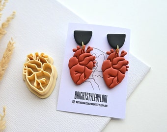 Op de afbeelding: Een paar rode hartvormige oorbellen met zwarte en gouden accenten. De oorbellen worden getoond op een witte kaart met de tekst "BRIGHTSTYLEBYLORI" en "instagram.com/brightstylebylori".