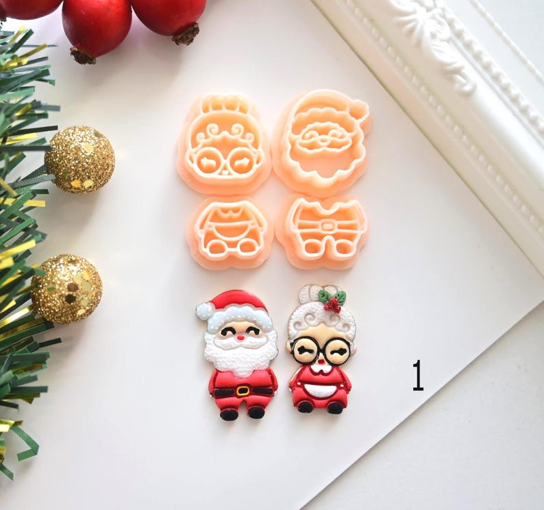 K&ouml;nnte beinhalten: Eine Sammlung von weihnachtlichen Ausstechformen und dekorativen Figuren. Die Ausstecher haben die Form von Weihnachtsmann und Frau Claus. Die Figuren zeigen Weihnachtsmann und Frau Claus in rot-wei&szlig;en Outfits. Die Zahl 1 befindet sich im Bild.