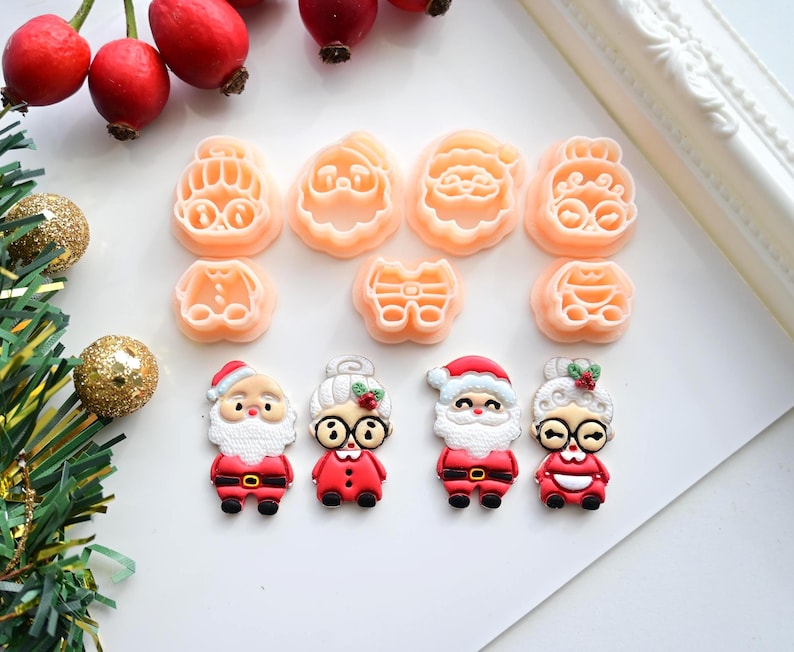 K&ouml;nnte beinhalten: Eine Sammlung von weihnachtlichen Ausstechern und dekorativen Figuren. Die Ausstecher haben die Form von Gesichtern des Weihnachtsmanns und der Weihnachtsfrau sowie andere festliche Designs. Die Figuren sind Weihnachtsmann und Weihnachtsfrau in roten Outfits.