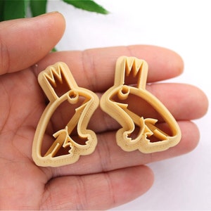 May include: Two brown plastic cookie cutters shaped like frogs wearing crowns.