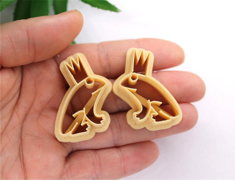 May include: Two brown plastic cookie cutters shaped like frogs wearing crowns.