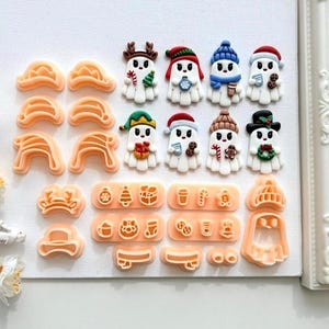 May include: An assortment of orange cookie cutters and ghost-shaped decorations. The white ghosts are adorned with festive hats and accessories, such as a reindeer, a Santa hat, and a scarf. The cookie cutters are in various shapes, including hats and ghosts.