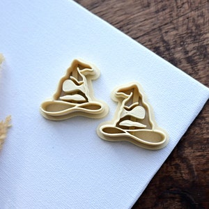 Op de afbeelding: Twee beige plastic koekjesvormen in de vorm van de Sorteerhoed uit de Harry Potter-serie.