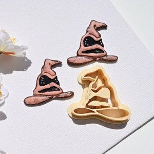 Op de afbeelding: Drie koekjesvormen in de vorm van de Sorteerhoed uit de Harry Potter-serie. De vormen zijn gemaakt van lichtbruin plastic en klaar om koekjes uit te steken.