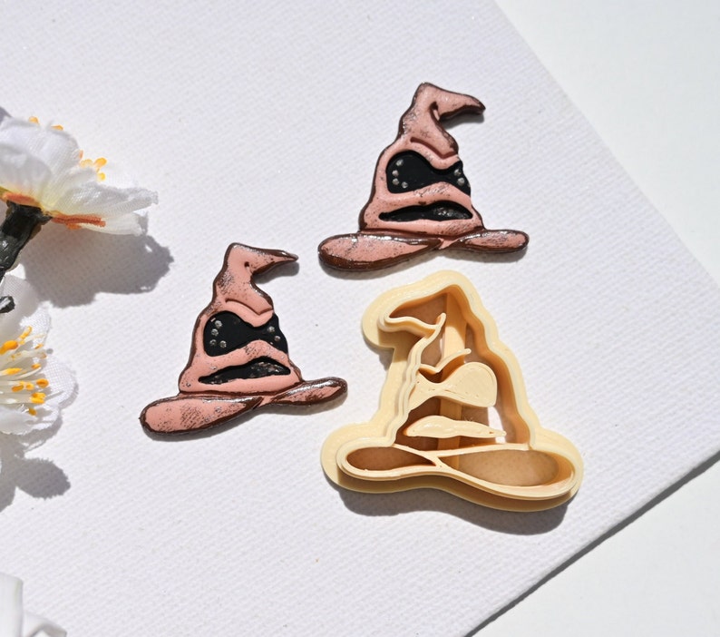 Op de afbeelding: Drie koekjesvormen in de vorm van de Sorteerhoed uit de Harry Potter-serie. De vormen zijn gemaakt van lichtbruin plastic en klaar om koekjes uit te steken.