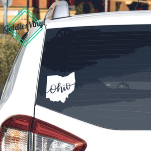 May include: White vinyl decal of the state of Ohio with the word "Ohio" written in cursive script on a car window.